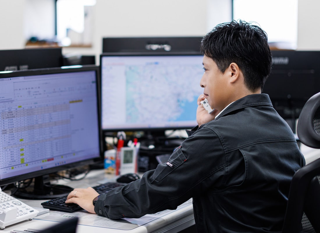 PCを見ながら電話で取引先とやり取りするタツミトランスポートのスタッフ