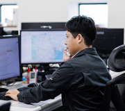 PCを見ながら電話で取引先とやり取りするタツミトランスポートのスタッフ